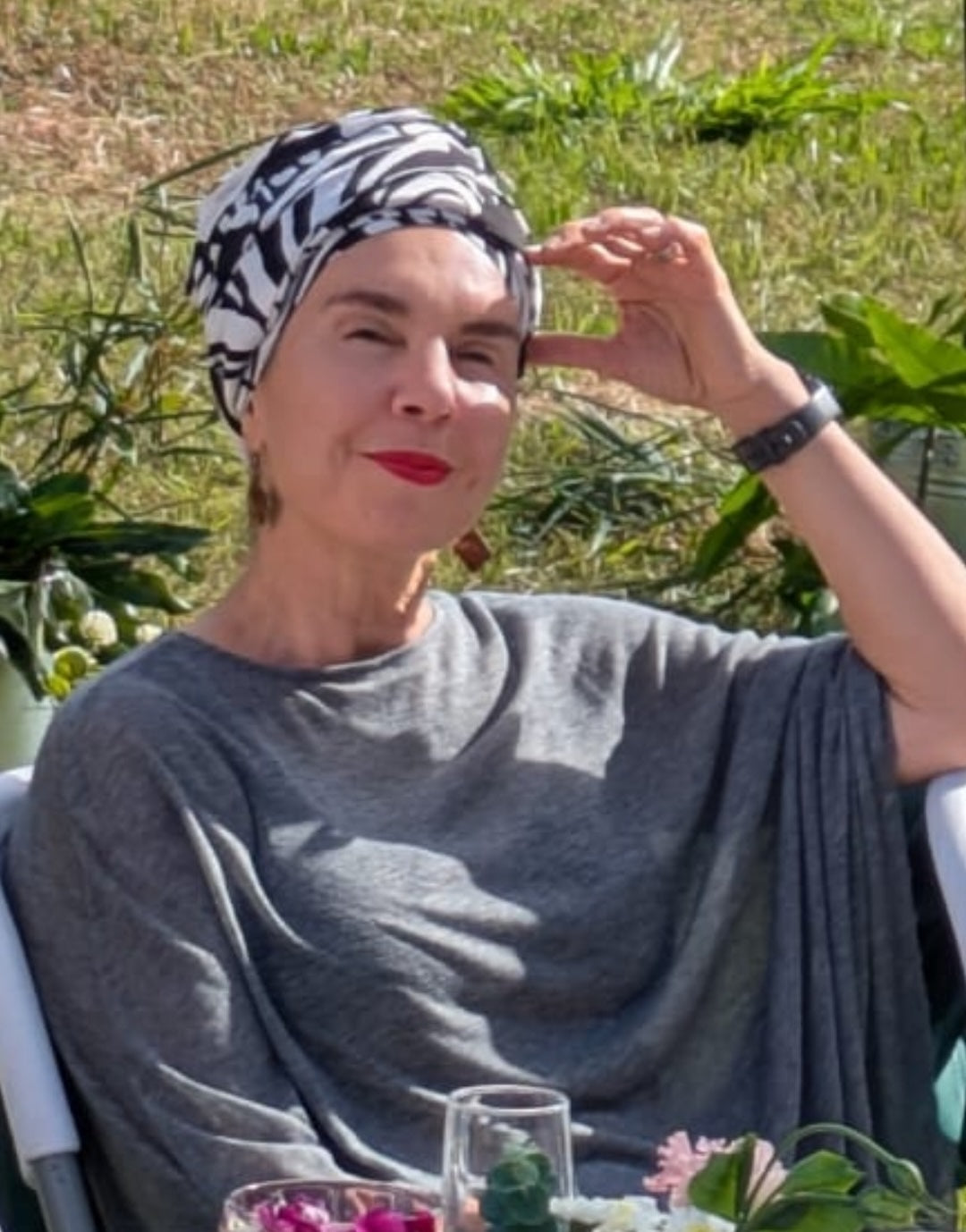Woman wearing a mint green metallic turban and sunglasses, seated on a zebra-print sofa