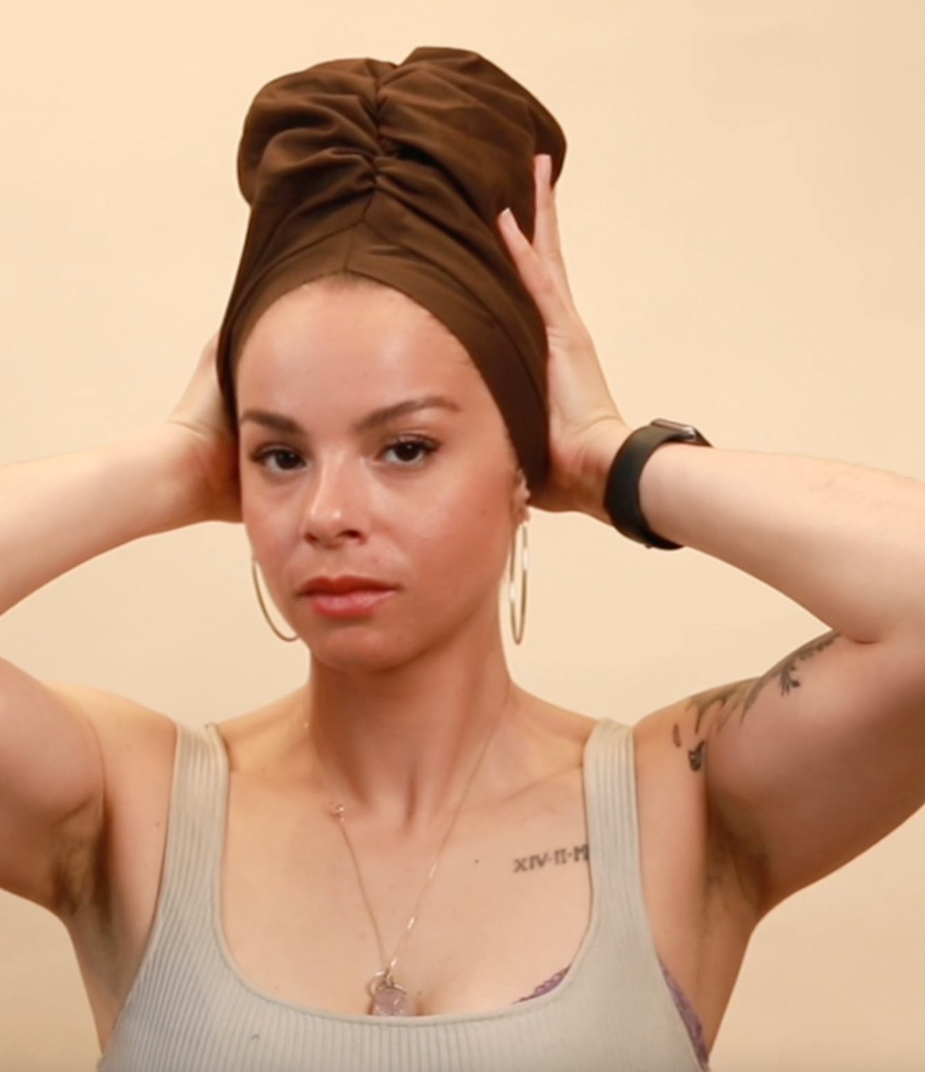 Woman wearing a brown satin-lined turban bonnet, hands resting on the bonnet