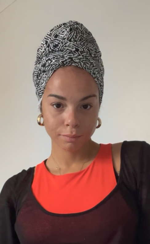 Woman wearing a black and white patterned turban, looking at the camera