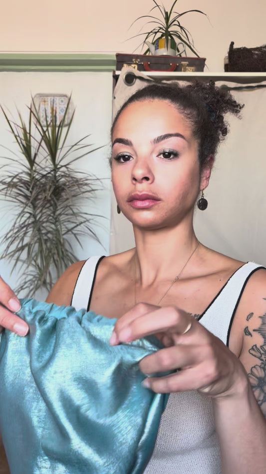 Video of a woman putting on the Halle Crown, a reversible blue metallic hair turban
